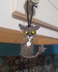 A photo of a cat-shaped woven ornament hanging on a knob.