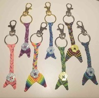 A photo of 7 fishtail mermaid keyrings in a variety of color schemes on a white background. Each tail features a plastic, slightly irridescent seashell button by the tailfins.