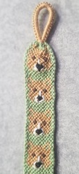 A keychain with a light brown corgi face on a pale green background