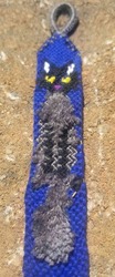 A bracelet with a silver loop with a gray and black fluffy cat body on a dark blue background