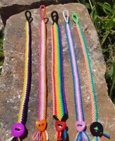 A photo of 5 pride flag stripe bracelets laid out on a brick in the sunshine