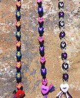 A photo of 3 pride flag themed heart bracelets laid out on a brick in the sunshine