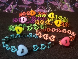 7 Black Bracelets with neon-colored Heart Designs stacked on top of one another