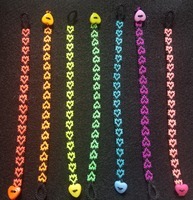 7 Black Bracelets with neon-colored Heart Designs layed next to each other in a row