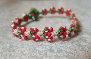 A bracelet made up of woven mushroom shapes.  The mushrooms are red-capped with white spots.  The stem is a beige color.
