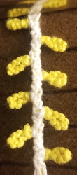 A photo of an unfinished bracelet that is woven to look like yellow holiday lights
