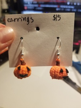 A pair of orange jack-o-lantern pumpkin earrings with silver findings.