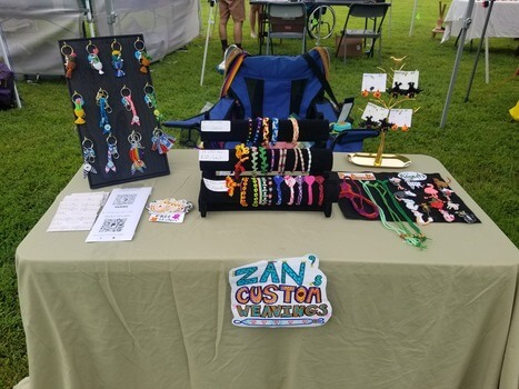 A picture of a table at an arts festival with multiple colorful weavings on displays.